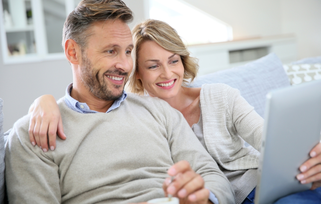 Middle-aged couple relaxing in sofa and using tablet